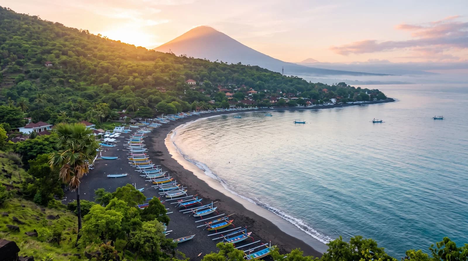 Amed coastline panorama: black sand, jukung boats and Mount Agung at dawn.
