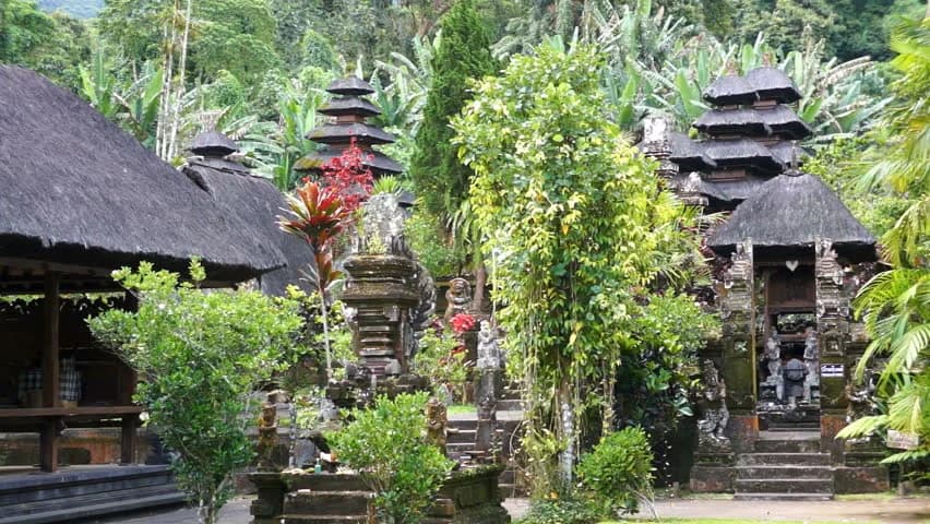 Serene landscape of Batukaru Temple Bali with lush jungle, showcasing traditional stone temples amid hills.