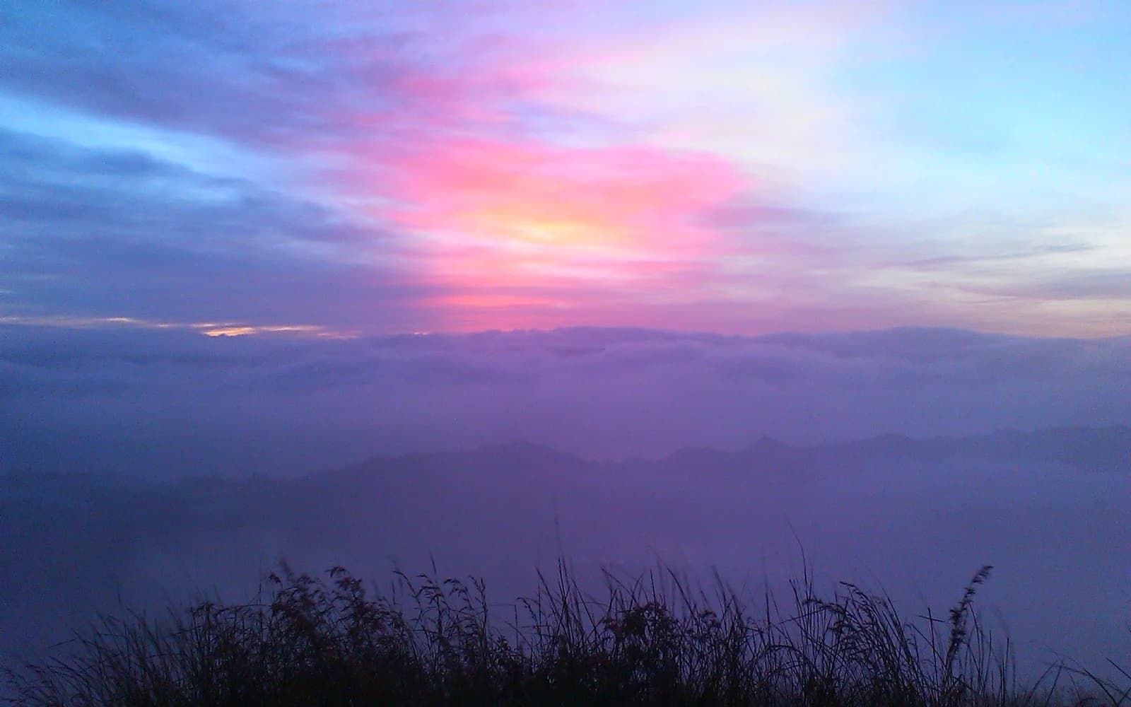 Stunning sunrise over Mount Batur during a Batur Tour, revealing misty valleys and vibrant skies in Bali.