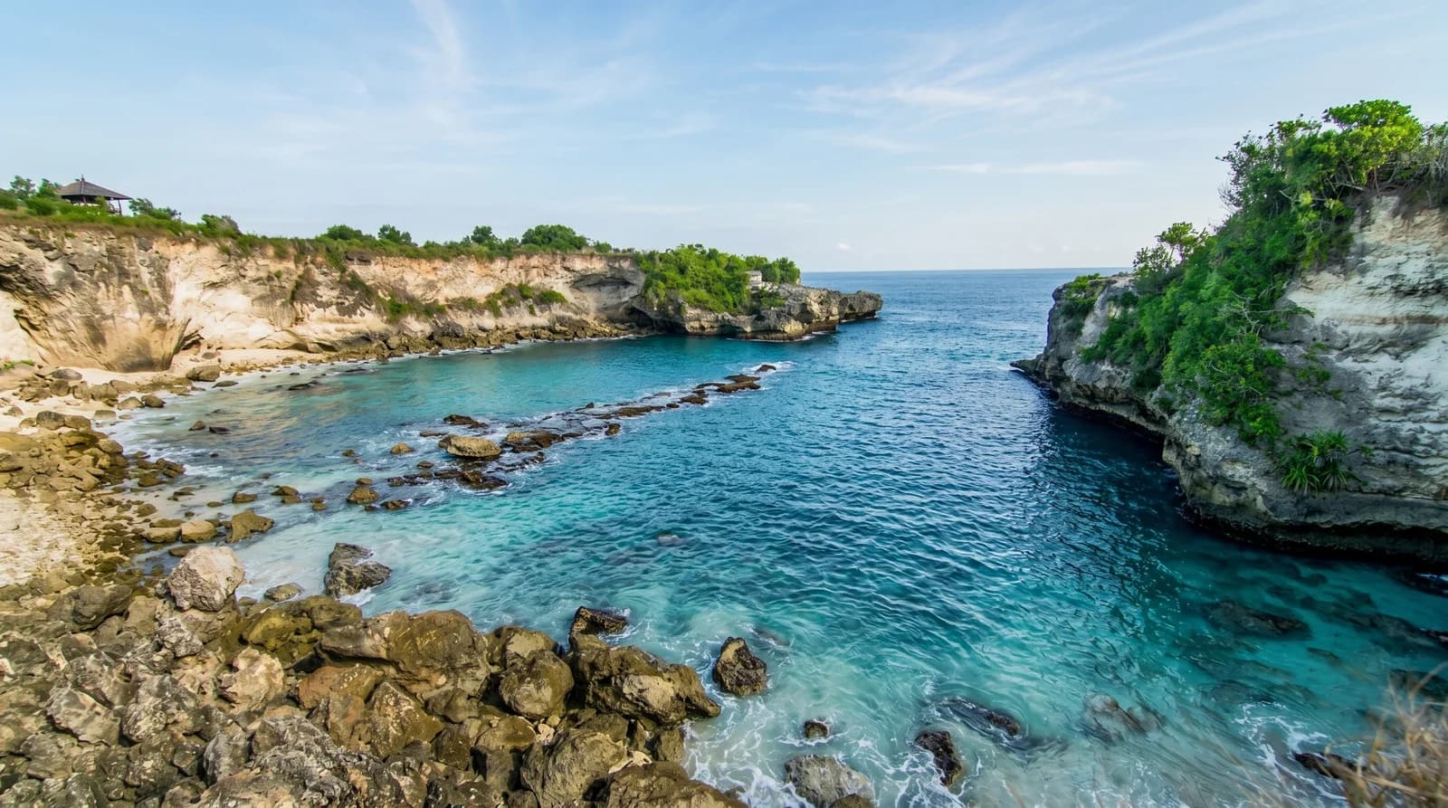 Tranquil Blue Lagoon (Ceningan) landscape with turquoise waters and rocky cliffs, ideal for Bali tours and relaxation.