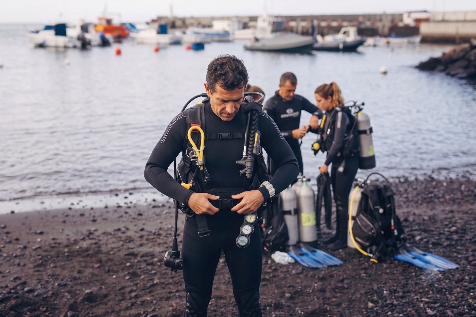 A diver putting on scuba gear on the beach before a dive