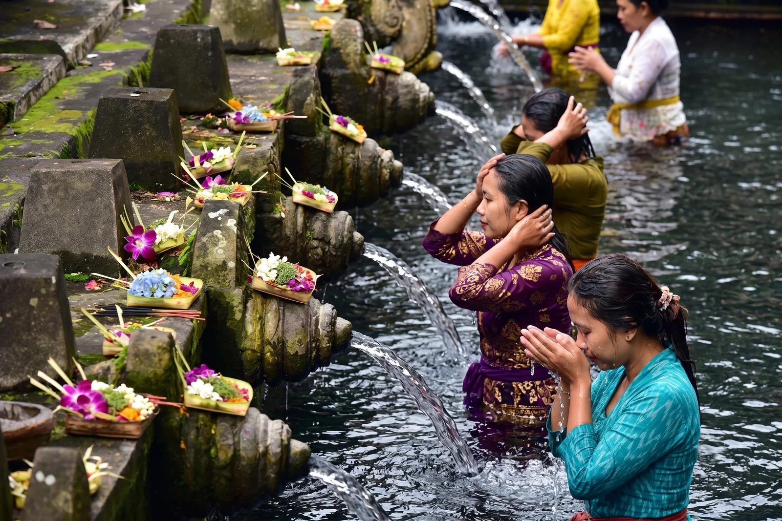 Pilgrims performing the melukat purification ritual under spring spouts at Tirta Empul
